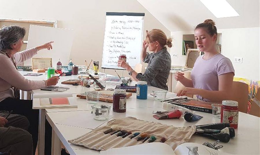 Trois femmes dans un studio d'art avec des pinceaux en premier plan
