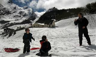 Enfant jouant dans le neige en face des montagnes.