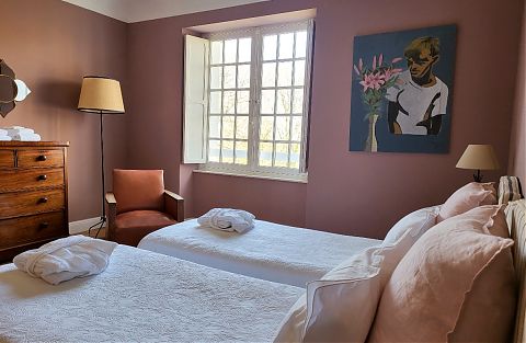 Chambre avec lits jumeaux et couvertures blanches, murs rose foncé.